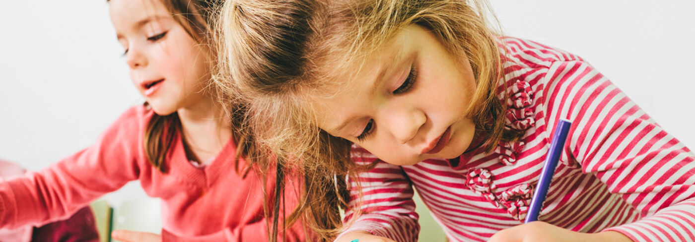 Two girls with red shirt painting on a paper